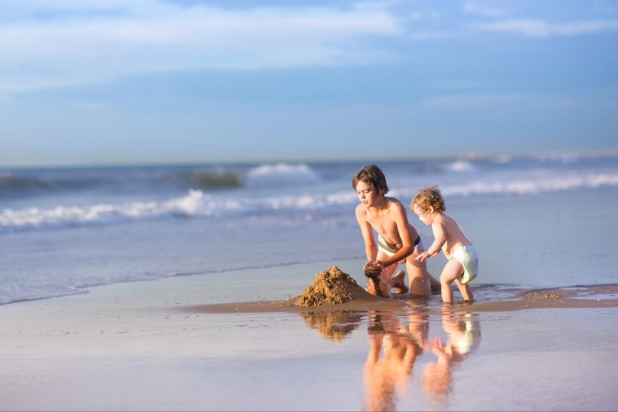 Kinder am Meer bauen eine Sandburg
