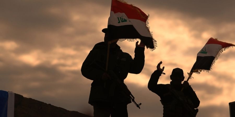 ARCHIV - Kämpfer von Milizen im Irak, die vom Iran unterstützt werden, schwenken irakische Flaggen. Foto: Anmar Khalil/AP/dpa