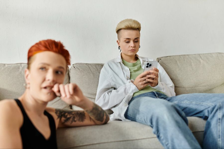 Zwei Frauen, eine am Smartphone auf dem Sofa