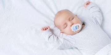 baby schläft mit armen über dem kopf