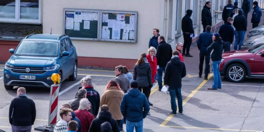 Hier ist Geduld gefragt: Apotheker und Mitarbeiter von Versorgungsbetrieben stehen auf dem Gelände des Zuckerwerks in Anklam in einer langen Schlange am Verkaufsbüro an. Foto: Jens Büttner/dpa-Zentralbild/dpa