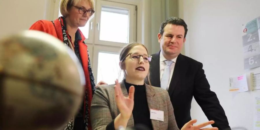 Hubertus Heil (r) und Anja Karliczek besuchen die Zentrale Servicestelle Berufsanerkennung bei der Zentralen Auslands- und Fachvermittlung (ZAV). Mitarbeiterin Jana Braun (m) erzählt über ihre Arbeit. Foto: Oliver Berg/dpa