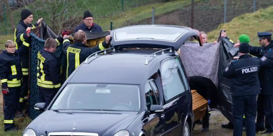 Einsatzkräfte verhindern mit Sichtschutztüchern unerwünschte Blicke. Foto: Swen Pförtner/dpa