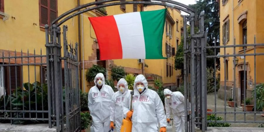 Arbeiter in Schutzkleidung desinfizieren Gehwege in Rom. Foto: Mauro Scrobogna/LaPresse/dpa
