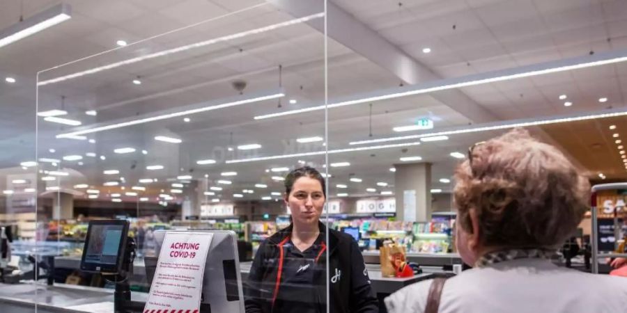 In einem Supermarkt in Rheinfelden in Baden-Württemberg wird die Kassiererin von einer Plexiglasscheibe geschützt. Foto: Philipp von Ditfurth/dpa