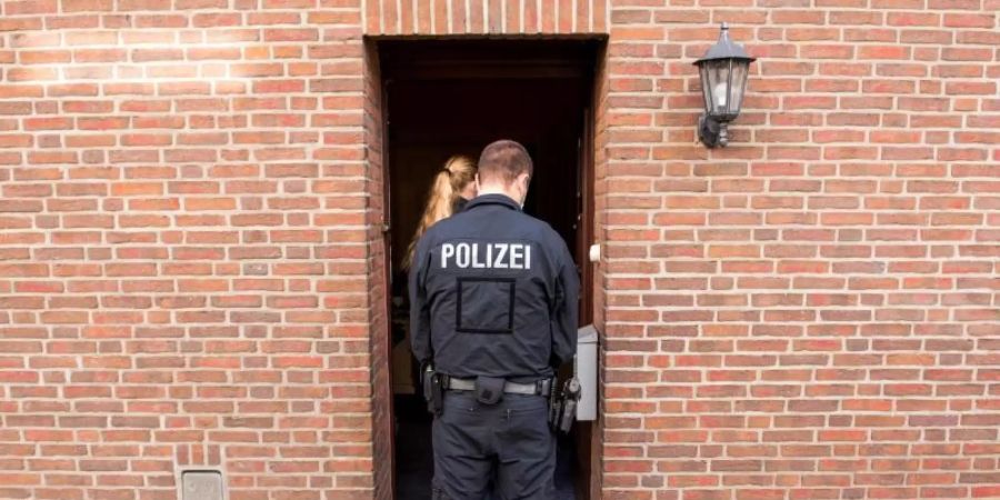 Einsatzkräfte vor einem Wohnhaus in Norderstedt. Objekte in Hamburg, Niedersachsen und Schleswig-Holstein wurden durchsucht. Foto: Daniel Bockwoldt/dpa