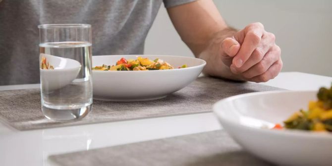 Teller weiss Essen vielfarbig Glas mit Wasser Tisch