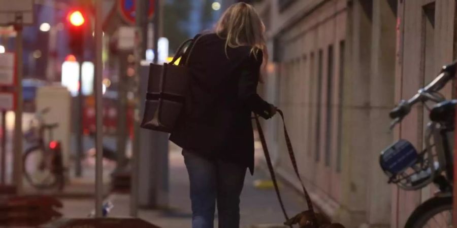 Eine Frau in Düsseldorf geht am Abend mit ihren Hunden spazieren. Foto: David Young/dpa