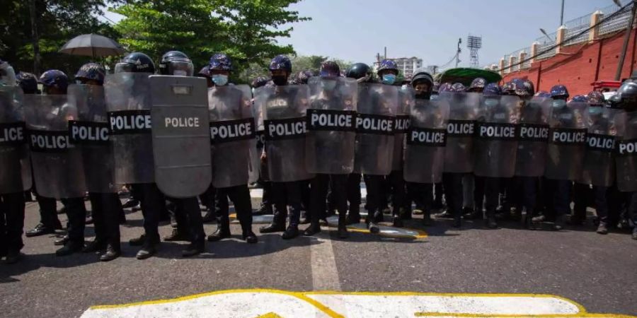 Polizisten blockieren eine Strasse, auf die ein Dreifingergruss als Zeichen des Widerstands gezeichnet ist. Foto: Theint Mon Soe/SOPA Images via ZUMA Wire/dpa