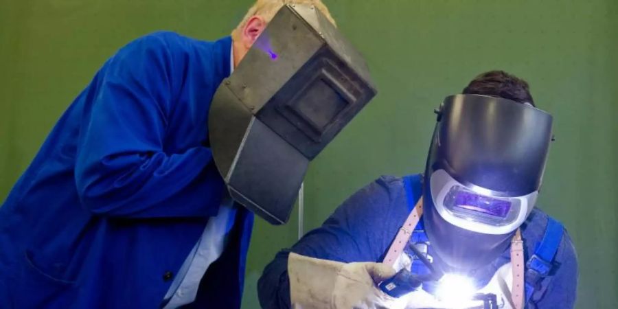 Ein Auszubildender setzt eine Schweissnaht an ein Metallteil, während ein Berufsschullehrer zuschaut. Laut Bildungsministerin Karliczek sollen «in nächster Zeit vor allem die Lehrkräfte in den Berufsschulen» weitergebildet und «auch die Ausstattung der Berufsschulen» verbessert werden. Foto: picture alliance / dpa