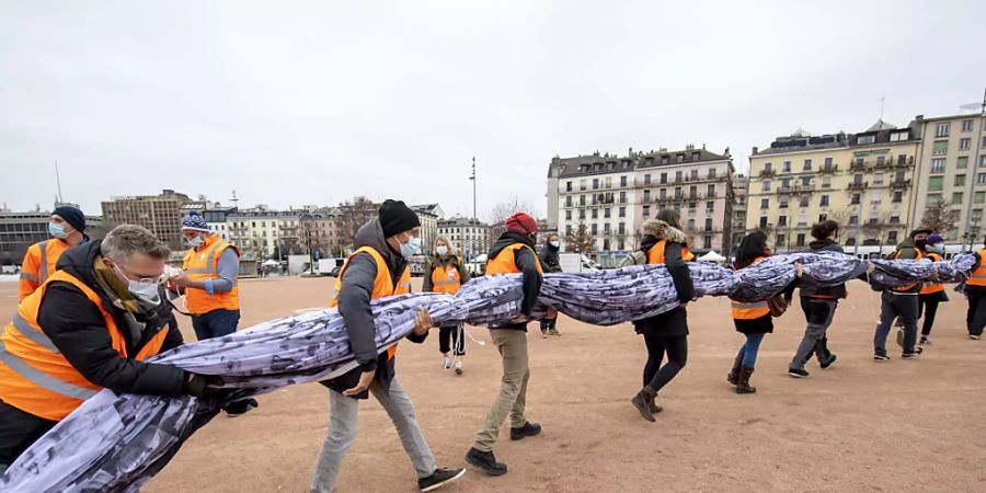 Freiwillige helfen mit die «We are watching»-Fahne in Genf zu entfalten. Quelle: KEYSTONE Fotograf: MARTIAL TREZZINI