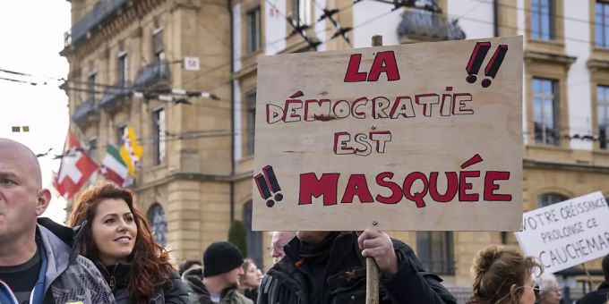 «Die Demokratie ist maskiert»: Demonstrantinnen und Demonstranten in Neuenburg. «Die Demokratie ist maskiert»: Demonstrantinnen und Demonstranten in Neuenburg.