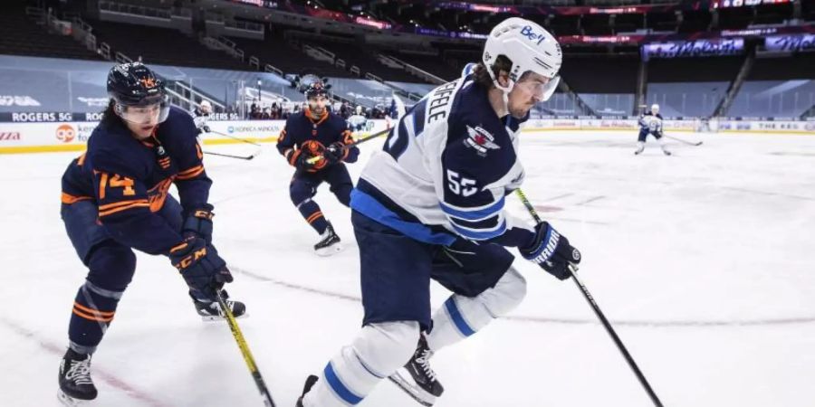 Ethan Bear (74/l) von den Edmonton Oilers versucht Mark Scheifele (55/r) von den Winnipeg Jets, den Puck abzunehmen. Foto: Jason Franson/The Canadian Press/AP/dpa