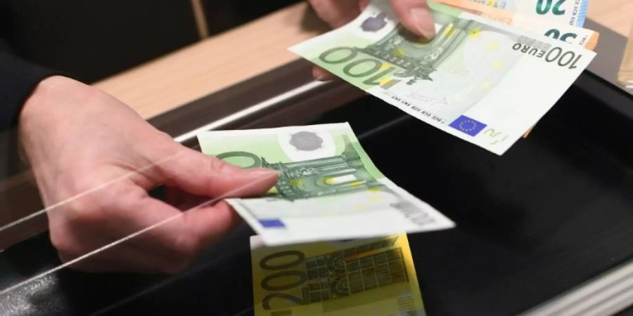 Frau lässt sich an Bankschalter Bargeld auszahlen