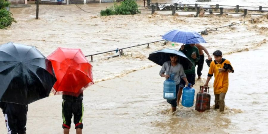 Bewohner Kathmandus waten durch die Wassermassen