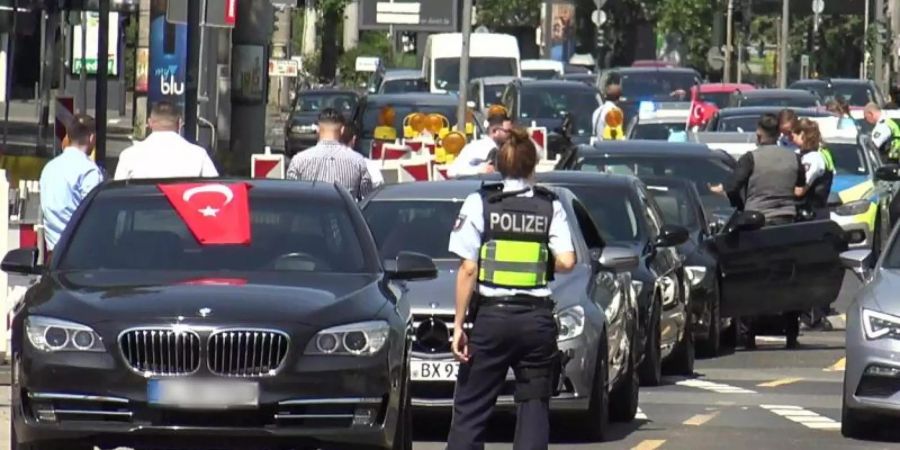 Eine Polizistin steht vor den Fahrzeugen eines türkischen Hochzeutskorsos. Der Konvoi war einer von dreien, den die Polizei in der Rheinmetropole am Wochenende angehalten hat. Foto: Thomas Kraus