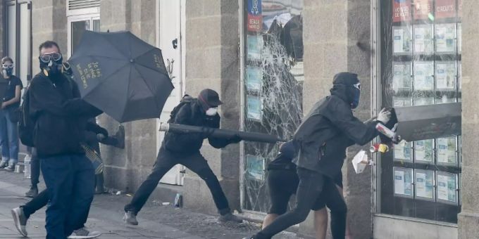Demonstranten in Nantes schlagen ein Schaufenster ein. gelbwesten
