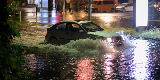 Ein Auto fährt nach einem Gewitter mit heftigem Regen durch die überflutete Strasse in Berlin. Unwetter