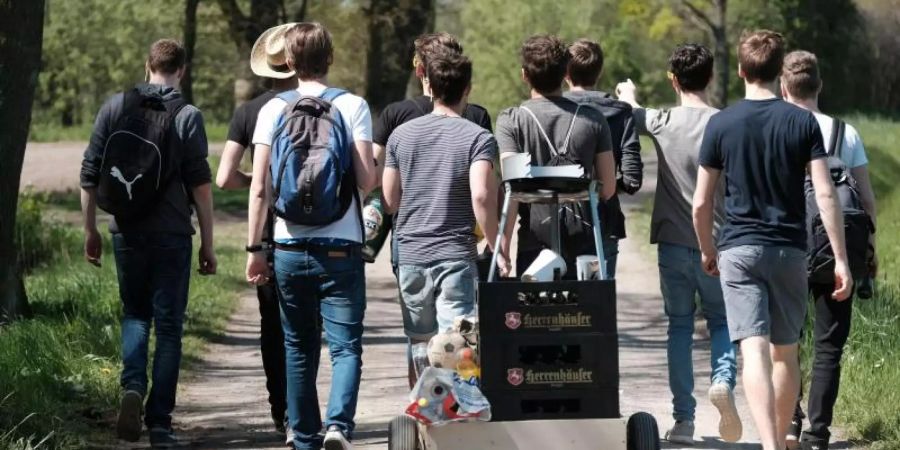 Eine Gruppe junger Männer feiert den Vatertag mit einem mit Bier gefüllten Bollerwagen. Foto: Peter Steffen