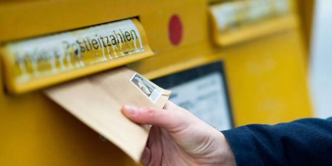 Mann an einem Briefkasten Briefkasten