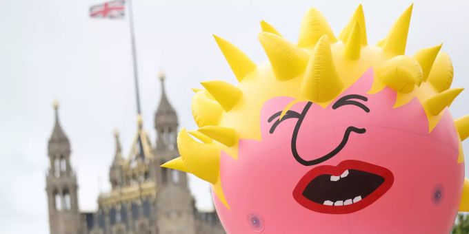 Ein Ballon, der den Politiker Boris Johnson darstellen soll, fliegt vor einem Protestzug von EU-Befürwortern in der Höhe. Im Hintergrund ist der Palace of Westminster mit einer gehissten, britischen Flagge zu sehen. boris johnson