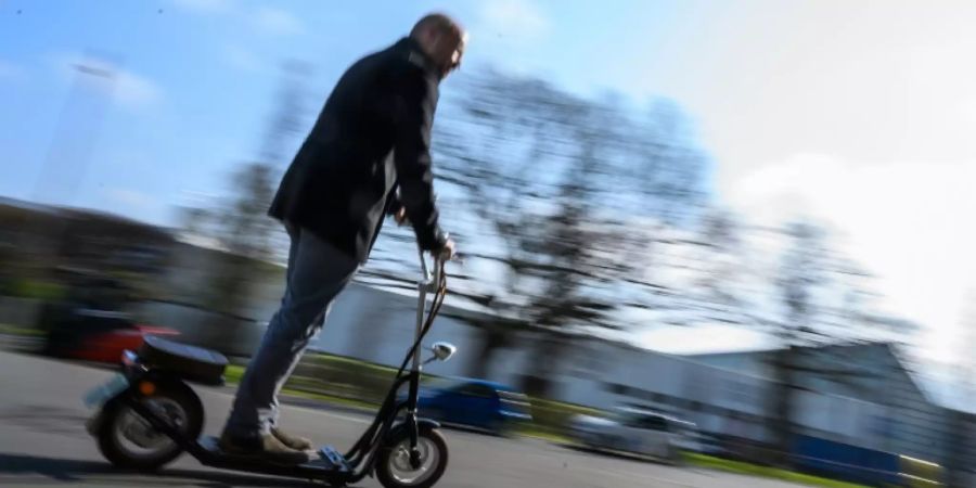 Mann fährt mit E-Tretroller