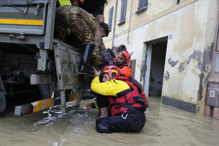 Feuerwehrleute retten einen älteren Mann in dem überfluteten Dorf Castel Bolognese.