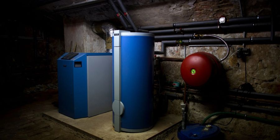 Ein Heizkessel und ein Warmwasserboiler stehen in einem Heizkeller in Dresden.
