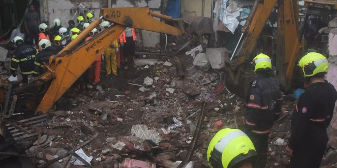 Feuerwehrleute stehen vor dem Haus, dass komplett in sich zusammenfiel und zahlreiche Menschen unter sich begrub. Building collapse in Mumbai after heavy rainfall