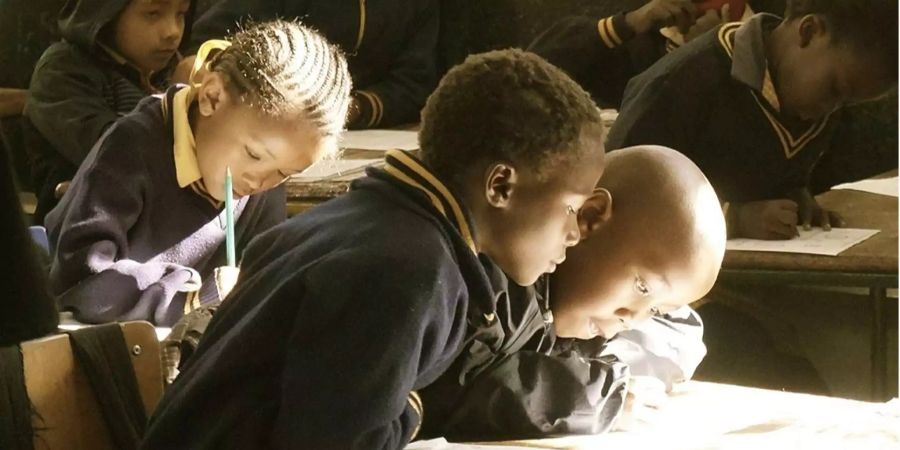 Bild aus einer afrikanischen Schule, bei den zwei Jungen angeregt über ein Blatt Papier schauen. (Symbolbild)