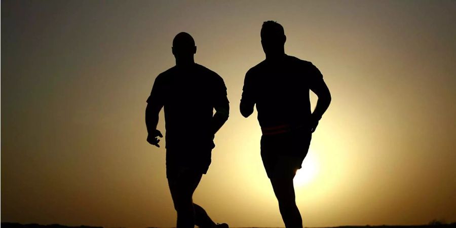 Die Silhouetten zweier Männer beim Rennen sind zu sehen.
