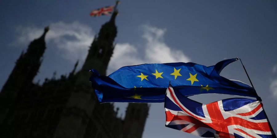 Eine EU-Flagge und eine britische Nationalflagge, der Union Jack, wehen vor dem britischen Parlament im Palace of Westminster, während eine Demonstration gegen den Brexit stattfindet.