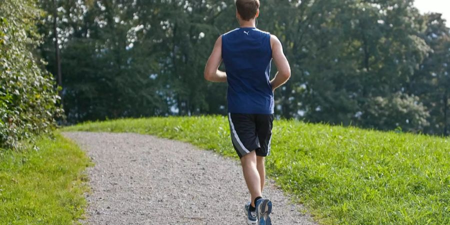 Ein Jogger rennt auf einer Landstrasse.