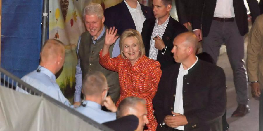 Hillary und Bill Clinton schlendern gemütlich durch die Wiesn und winken den Besucherinnen und Besuchern zu.