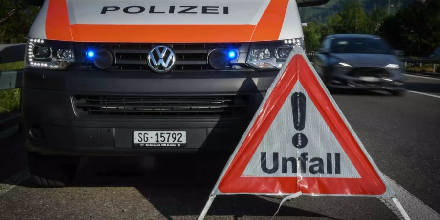 Unfall Warndreieck auf der Strasse neben einem Polizeiwagen - Keystone