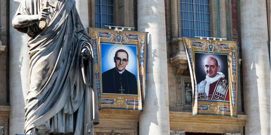 Die Wandteppiche des römisch-katholischen Erzbischofs Oscar Romero (l.) und Papst Paul VI. (r.) hängen von einem Balkon an der Fassade der Peterskirche im Vatikan.