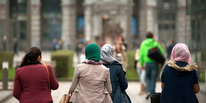 Junge Frauen, manche mit Kopftuch, laufen in der Innenstadt über einen Platz in Belgien. Junge Frauen, manche mit Kopftuch, laufen in der Innenstadt über einen Platz in Belgien.