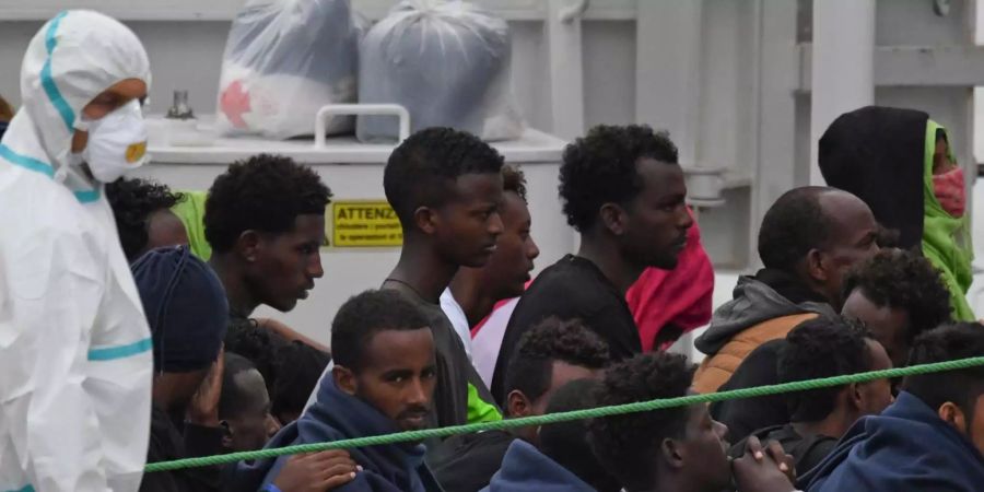 Migranten stehen an Deck des italienischen Küstenwachschiffs «Diciotti», das nach mehreren Tagen im Mittelmeer in den von Hafen Catania (IT) eingelaufen ist.