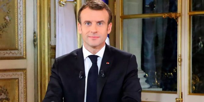 Der französische Präsident Emmanuel Macron lächelt vor seiner Fernsehansprache.