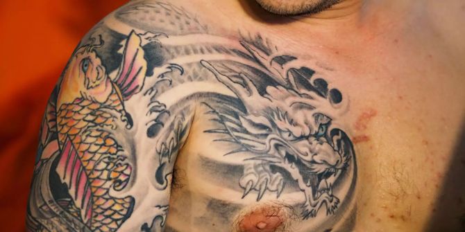 Ein Mann zeigt sein Brust- und Armtattoo beim einer Tattoo-Convention.