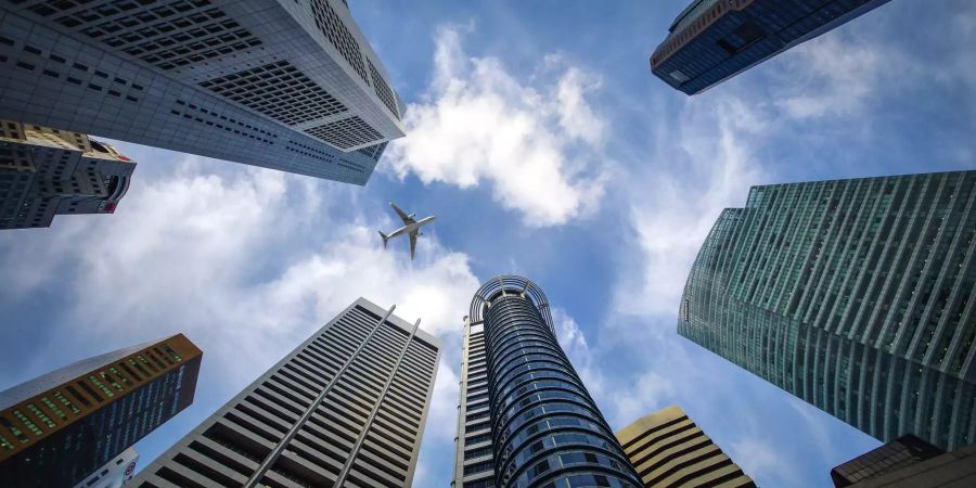 Ein Flugzeug fliegt über die Wolkenkratzer von Singapur.