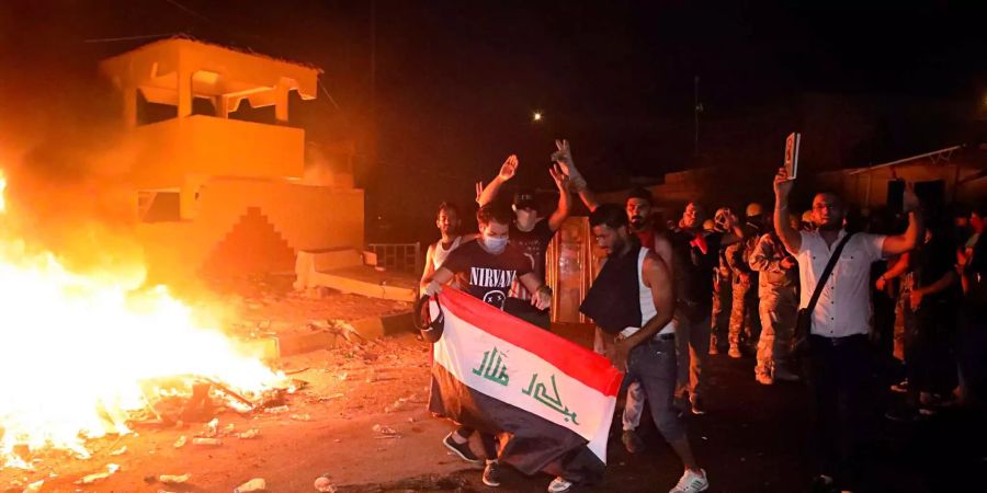 Teilnehmer einer Demonstration für bessere Dienstleistungen in der südirakischen Provinz Basra halten eine Nationalfahne, nachdem sie die Betonwände zum Einsturz gebracht haben, die das provinzielle Ratsgebäude umgeben.