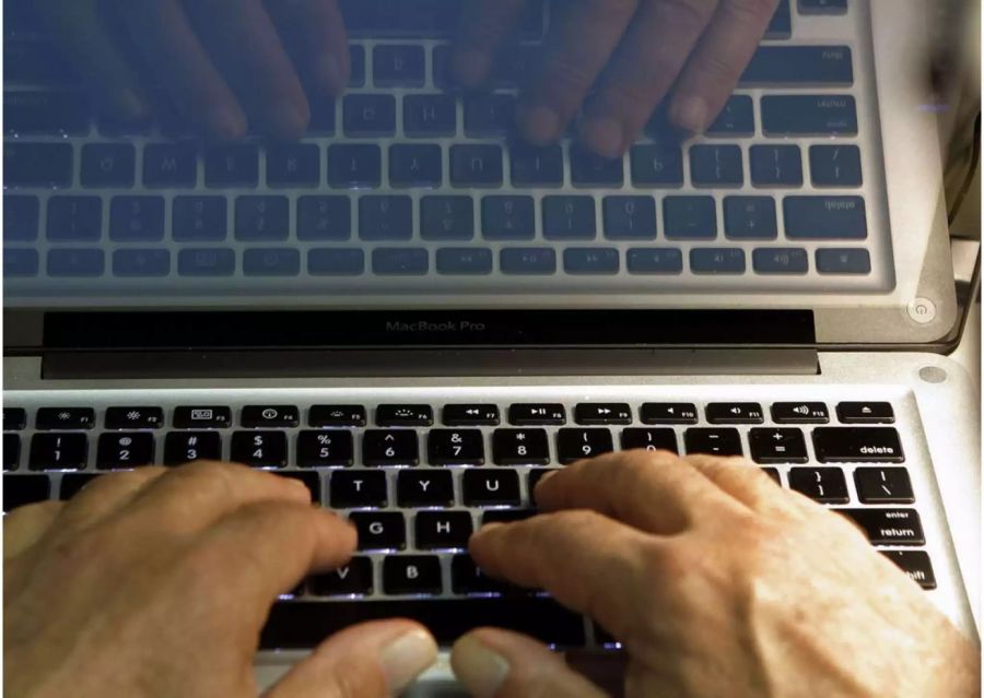Die Hände eines Mannes sind auf der Tastatur eines Mac Book Pro - Keystone