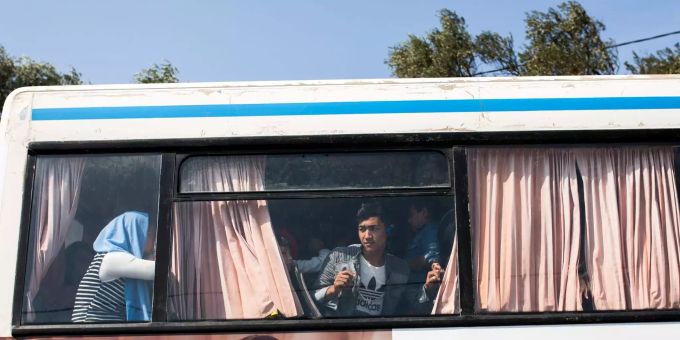 Ein junger Flüchtling aus Afghanistan schaut aus dem Fenster eines Busses, der vom Flüchtlingslager Moria fährt. flüchtling afghanistan