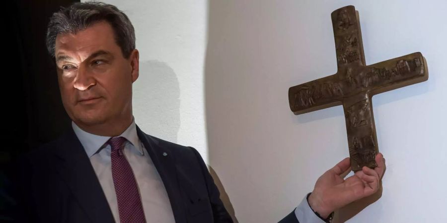 Markus Söder, Bayerischer Ministerpräsident (CSU), hängt ein Kreuz im Eingangsbereich der bayerischen Staatskanzlei auf.