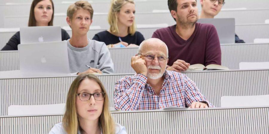 Ein älterer Student zusammen mit jüngeren Studenten während einer Vorlesung an der Universität Luzern.