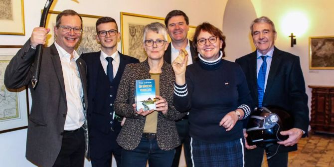 Eine Gruppe von schick gekleideten Personen stehen in einem Kloster