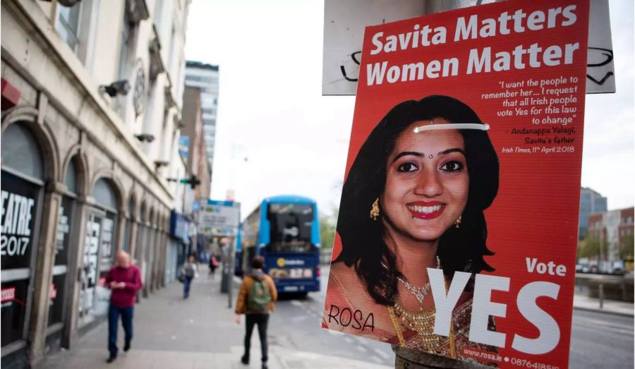 Das Poster zeigt ein Bild der indischstämmigen Savita Halappanawar. Die schwangere Frau war 2012 mit starken Schmerzen in ein Universitätsklinikum gegangen. Wenige Tage später starb sie an einer Blutvergiftung, nachdem die Ärzte ihre Bitte, den Fötus abzutreiben, abgeschlagen hatten.