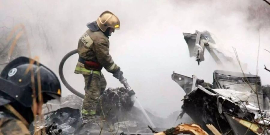 Feuerwehrmänner beim Löschen von brennenden Trümmerteilen eines Hubschraubers in Sibirien.