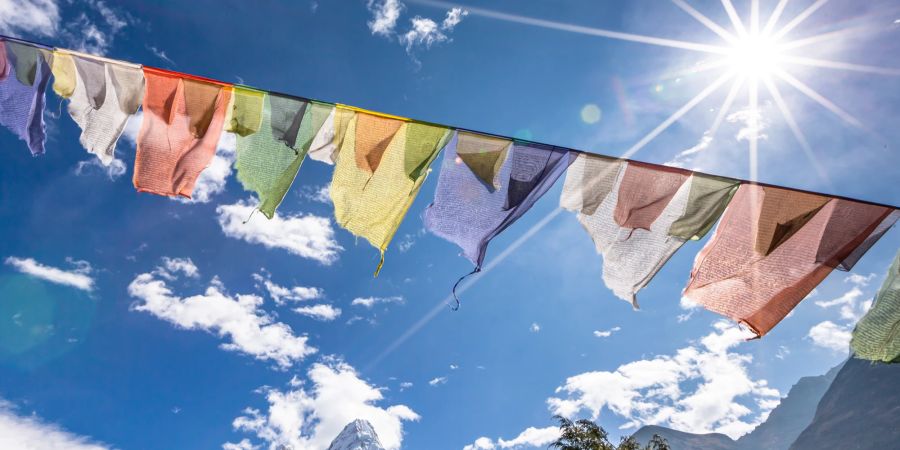 Bunte Flaggen von Buthan  vor blauem Himmel im Sonnenschein.